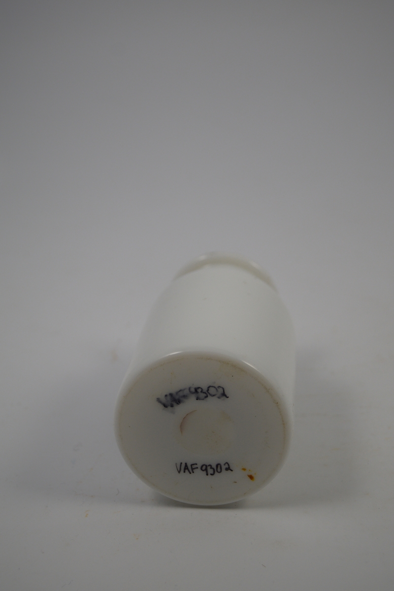 Porselenskrukke med propp. Sort oval etikett påført på krukken. Til oppbevaring av legemidler/pulver. Stoffet i krukken ble brukt til blant annet jernpreparat.