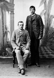 Portrett av to menn tatt i atelier, helfiguer. Den ene med l