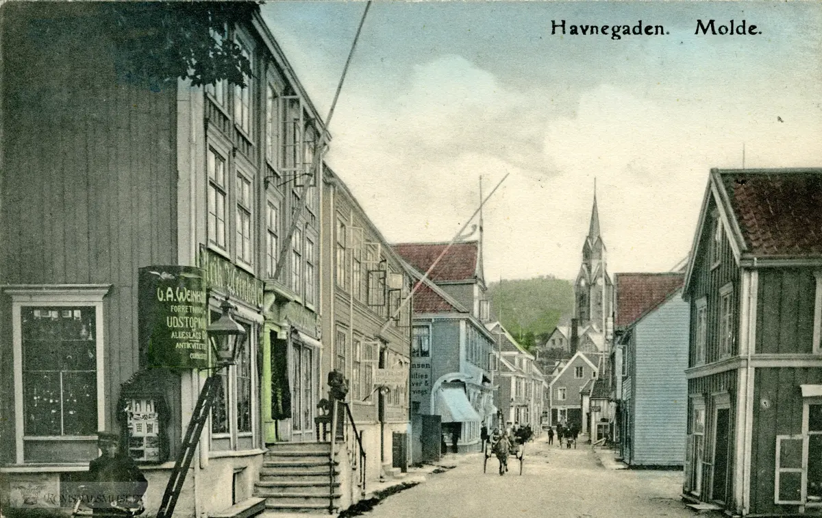 Storgata sett fra vest..Antikvitetshandler Ulrik Weinholdts butikk til venstre..Molde med kirken i bakgrunnen. .Ludvig Hansen sin butikk til venstre oppe i gata. .