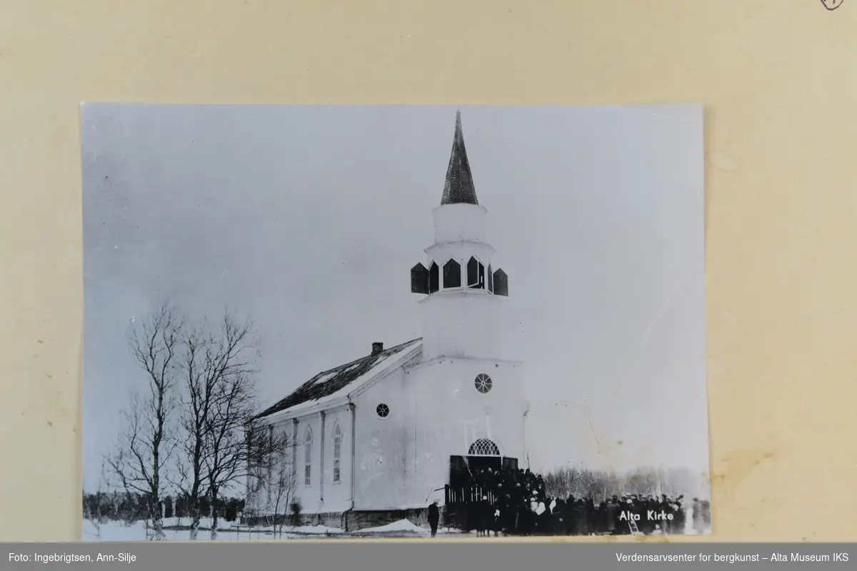 Motiv av Alta kirke. Bildet er tatt på vinteren, og på kirketrappa står det mange mennesker som er på tur inn i kirken. Panelene på kirkespiret står åpne.
