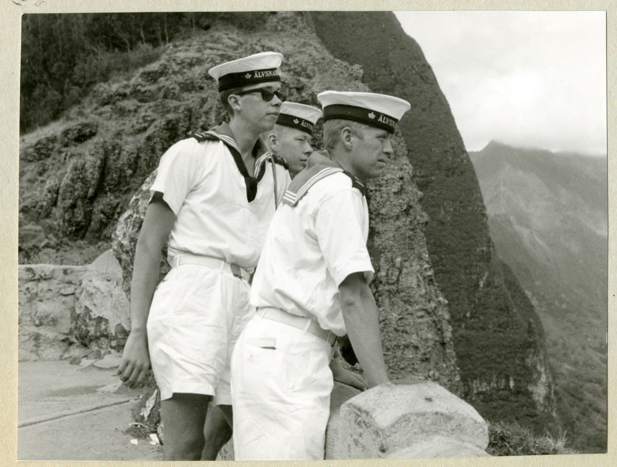 Bilden föreställer tre besättningsmän, iklädda sommaruniform, i ett berglandskap i samband med minfartyget Älvsnabbens långresa 1966-1967.