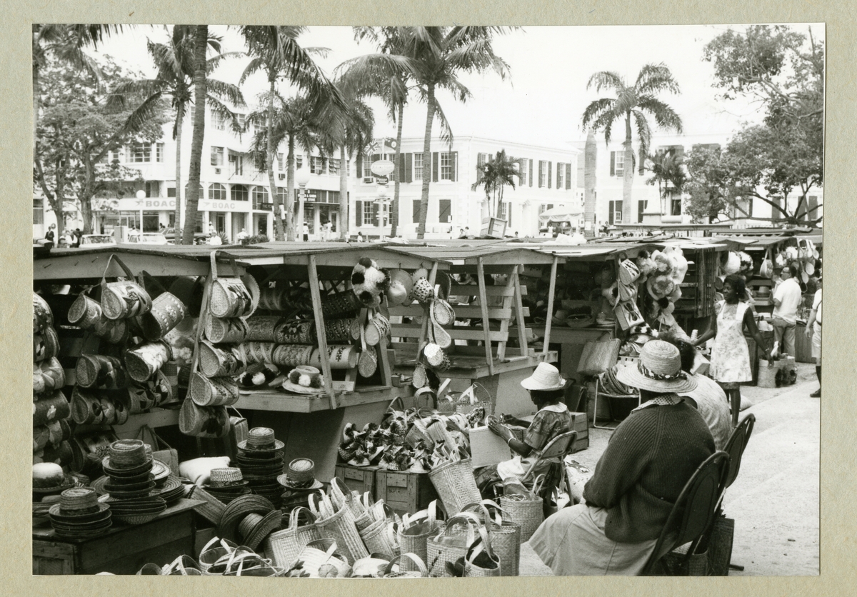 Bilden föreställer gatuförsäljning i Nassau. På bilden syns flera stånd med hattar och väskor. I bakgrunden syns palmer och bebyggelse längs med gatan. Bilden är tagen i samband med minfartyget Älvsnabbens långresa 1966-1967.