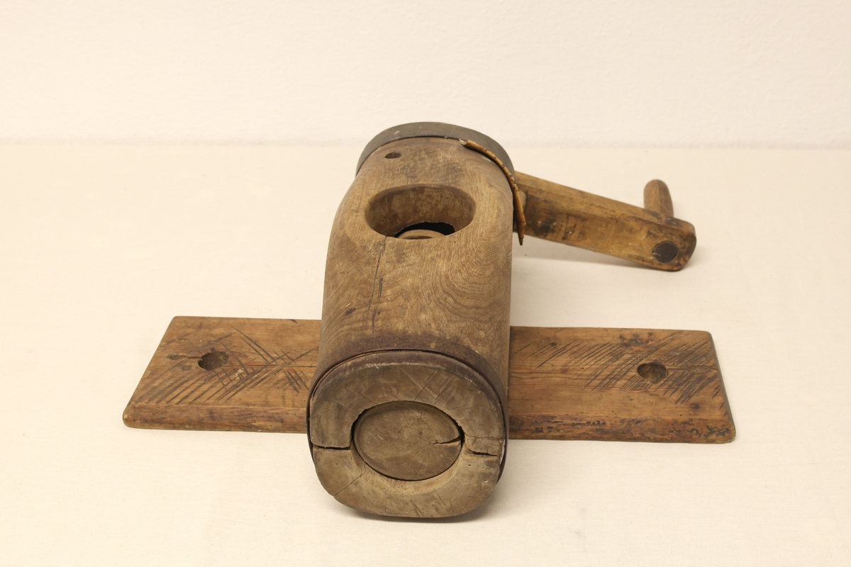 Potetkvern i tre. Kverna er laget av to trestokker som er hulet ut og satt sammen med jernbånd i begge ender. Skrue/Kall inni hulrommet, påmontert ei sveiv på utsiden. Kverna er festet til ei fjøl. Initialer og årstall er inngravert i sveiva.