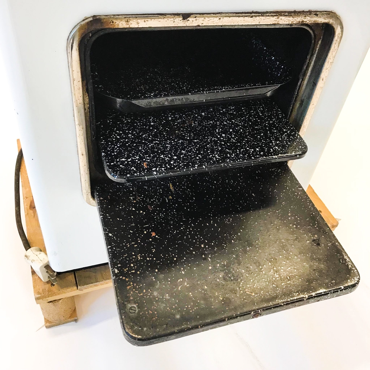 Elektrisk komfyr med bakvegg og tre kokeplater. Stekeovn med termometer på utsiden. I stekeovnen er det to tilhørende stekebrett. Lyspære på bakveggen.