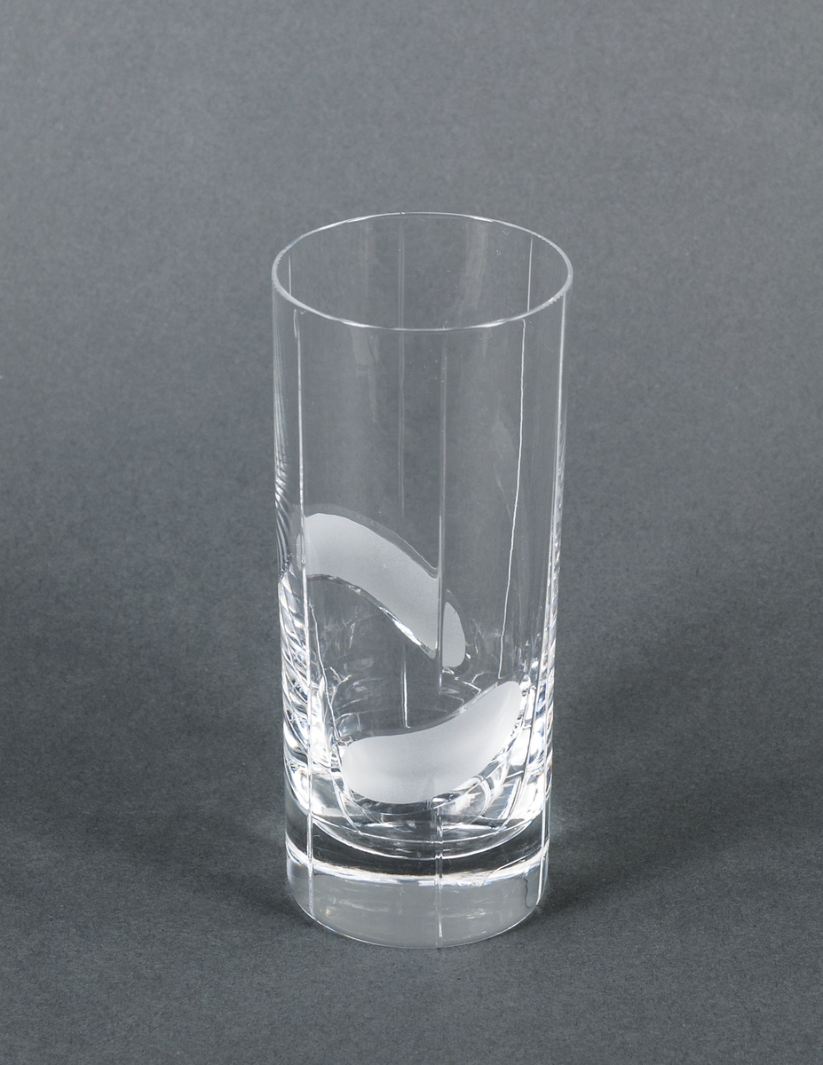 Ölglas, prov, ofärgat. Övre halvan cylindrisk med vertikala dekorränder och graverat tigermotiv. Nedre halvan slipad åttkantig.