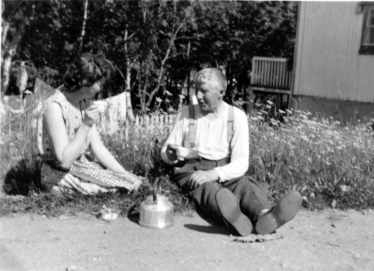 Kristian Elisar Rochmann og ei dame drikker kaffe ute. Stonglandseidet. Ca 1955.