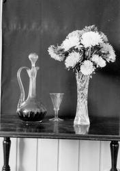 Stilleben, karaffell, glass og vase med blomster.
Skål med 