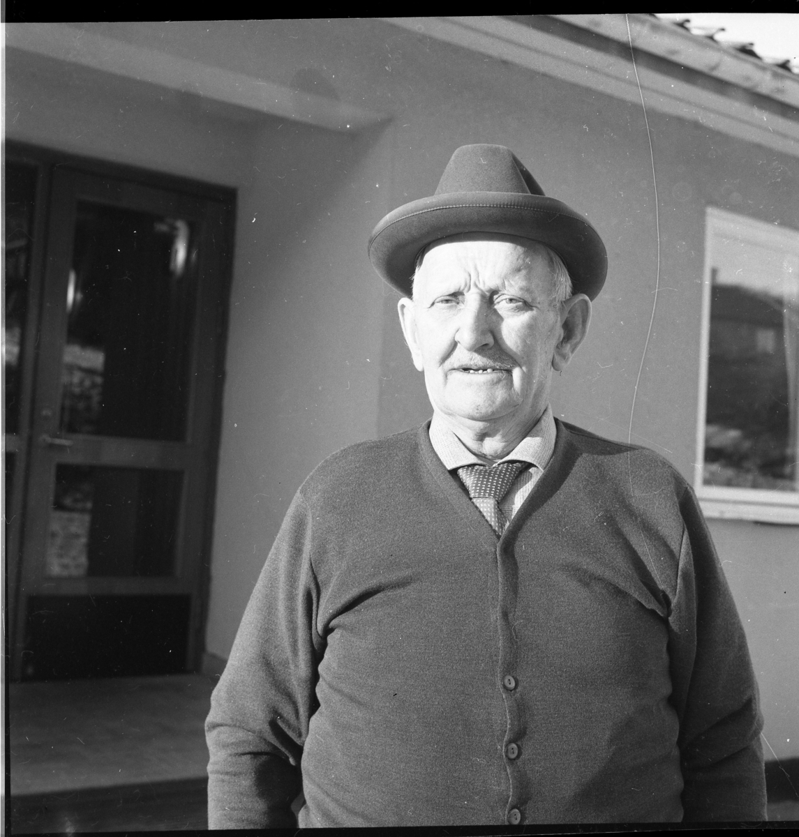 Karl Karlsson ("Kalle vacker"?), med hatt på huvudet, slips och cardigan, vid Mellbyro.