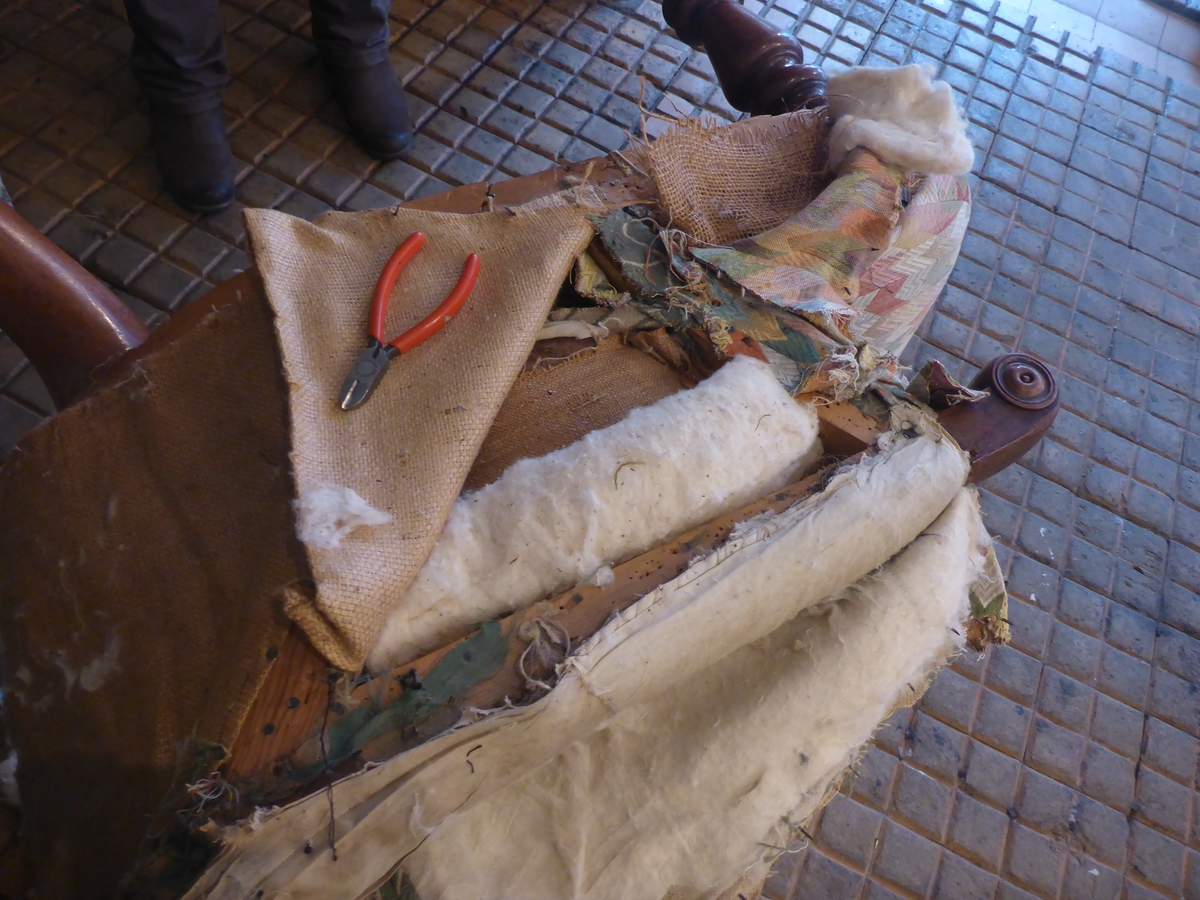 Stolen har en ramme av tre med dreide frambein som er beiset og oljet.