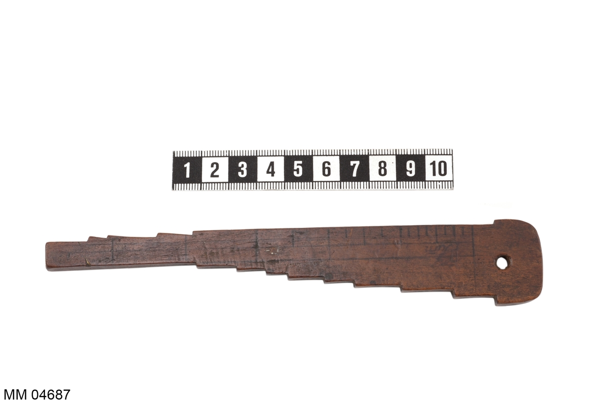 Hakmått för mätning av mynningen på eldrör till kanoner och mörsare. Av trä och polerat i brunt. Hakens antal 14 stycken, därav nio stycken märkta i svart: 1 u - 24 u.
Märkt i svart: Tillhör Winerled 1802.