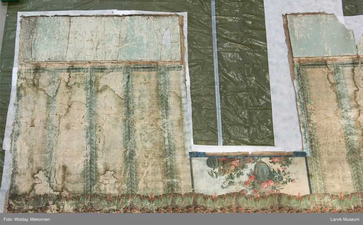 |Tapeten er påmalt tapetborder og brystning. Fra Hovland gård i Larvik.
Den øverste, brede borden: Gerlander/draperi med blomsterranker.
Den nederste, smalere borden: Tekstilbord med blomster. Øver døren til høyre: Stillebenmotiv med blomster og frukt.