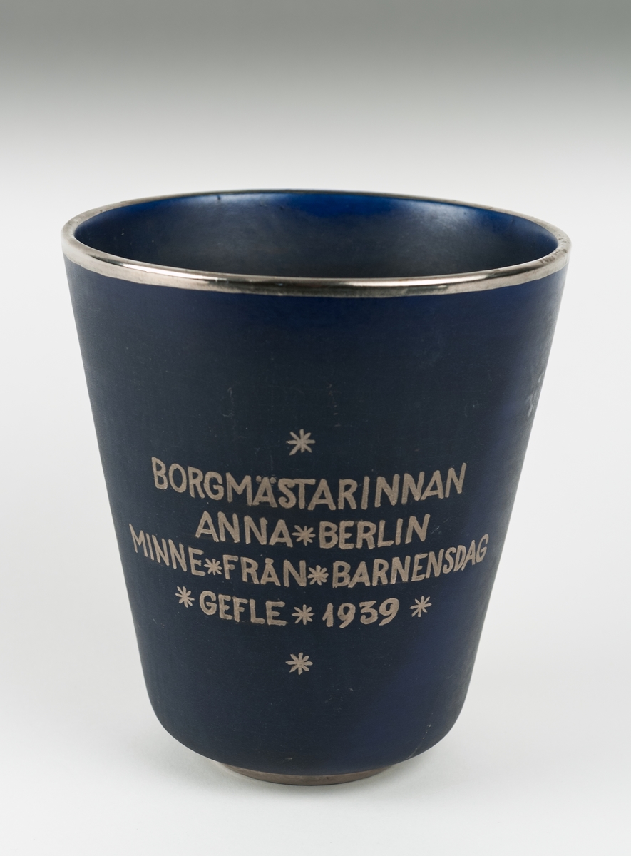 Märkt "Minnen från Barnens dag. Gefle 1939".
Blå vas med guldkant. Text i silverfärg.