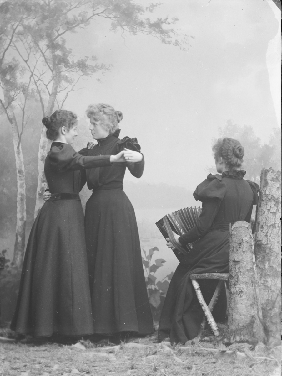 Kvinner, 2 som danser, 1 sitter og spiller trekspill, M.Baadstø, atelierbilde