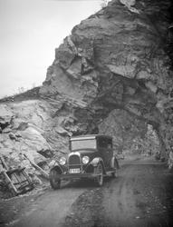 Bil ved en liten tunell. Arbeidstralle for jernbanespor ligg