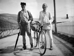 En mann med kortbukse og paraply og en med sykkel og lys dre