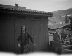 Jente og gutt ved uthus.