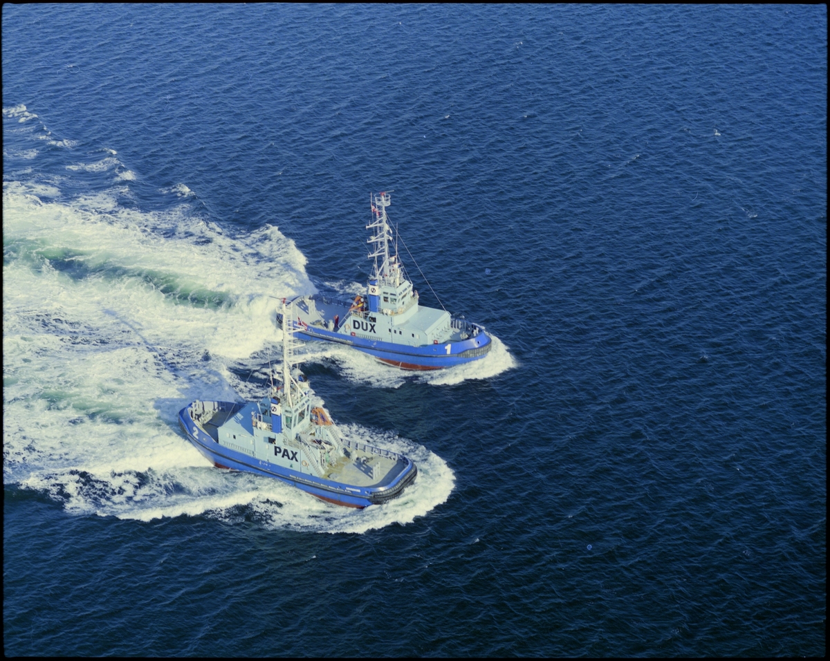 Flyfoto av Østensjø rederi sine søsterskip "Pax" og "Dux" ved Kårstø. Skipene kjører med full fart for- og akterover samtidig.