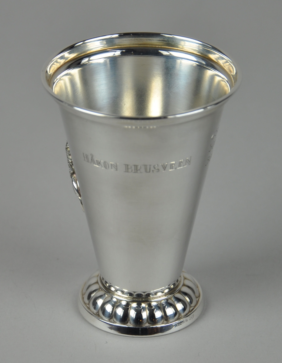 Pokal med dekor på stett og medaljong med bilde av et troll på sykkel