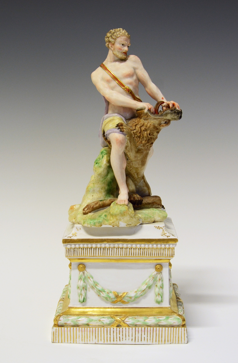 Herkules slåss mot en løve med bare hendene. Hans atributt, klubben ligger ved hans føtter, delvis under løven. De står på en underlag som imiterer gress. Under dette en kvadratisk sokkel med laurbærgirlandere i nyklassisistisk utførelse.