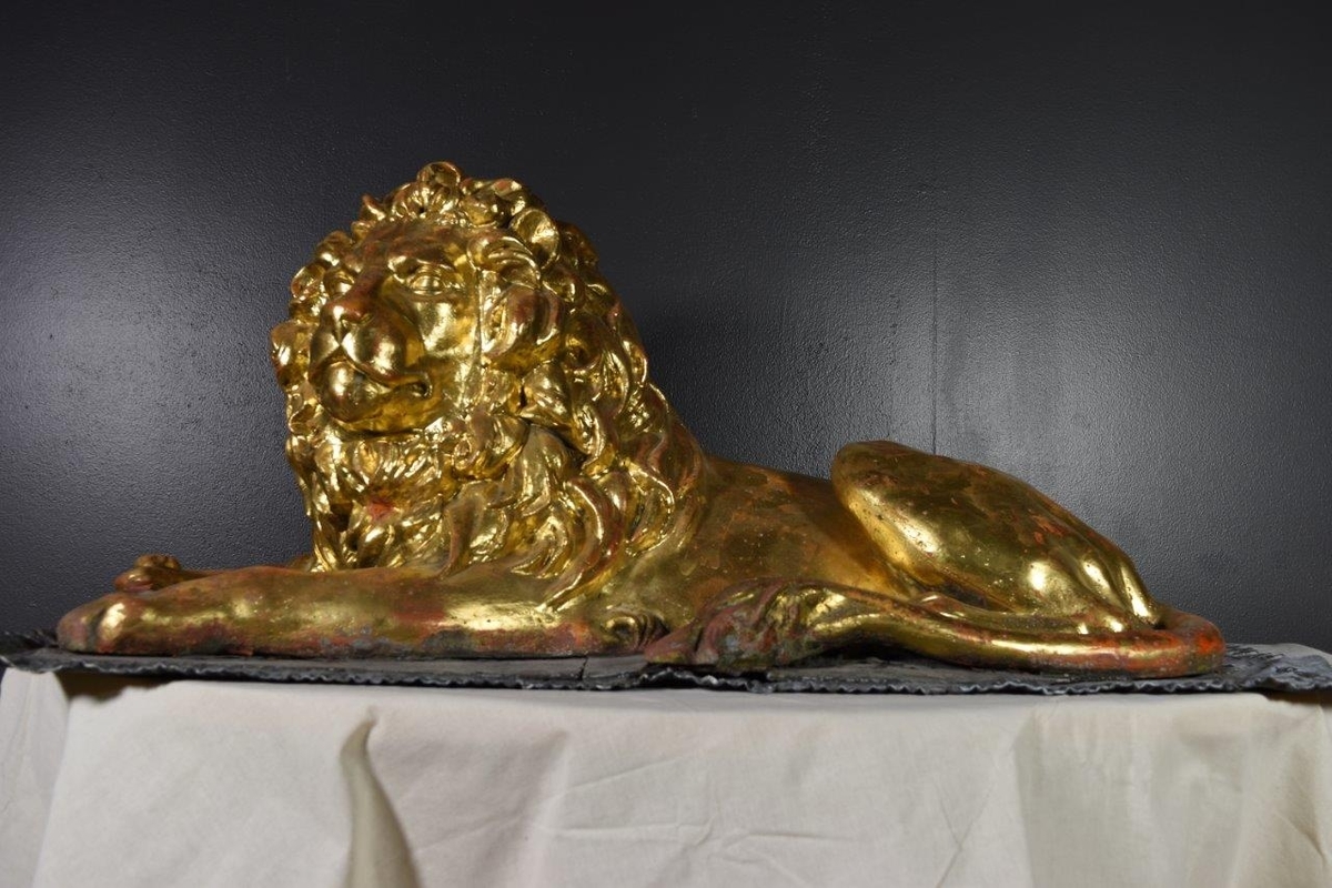 Løve-figur dekket med bladgull, liggende på en plate.