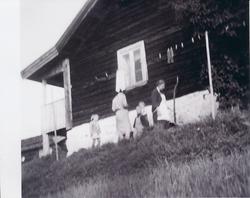 To voksne og to barn står utenfor en gammel stue.