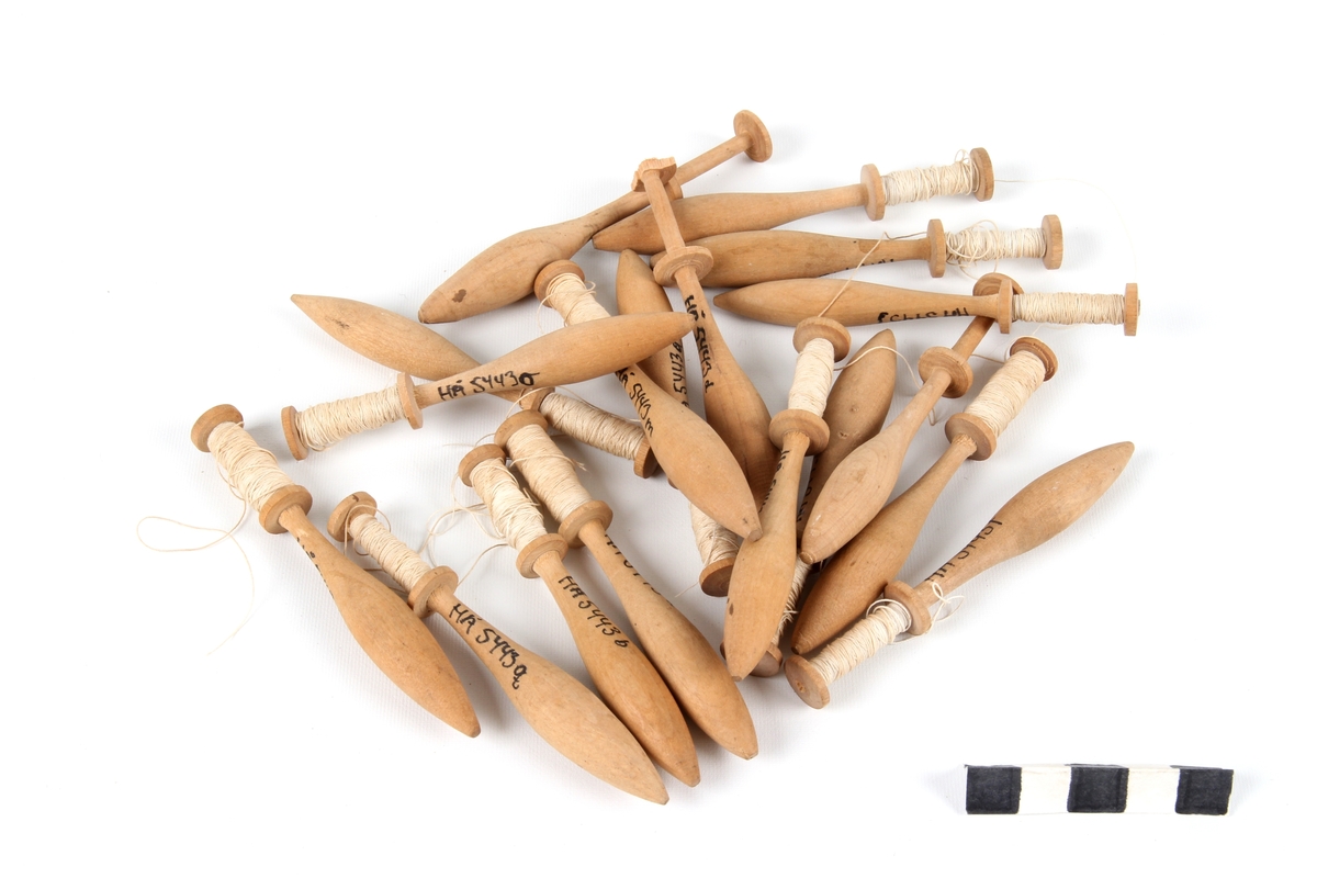 Atten ganske like kniplepinner i tre. De fleste med tråd og noen få uten.