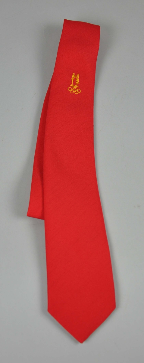 Rødt slips  med NOK/NIFsin  logo og de olympiske ringene påbrodert i sennepsgult.To like,som forrige nr.