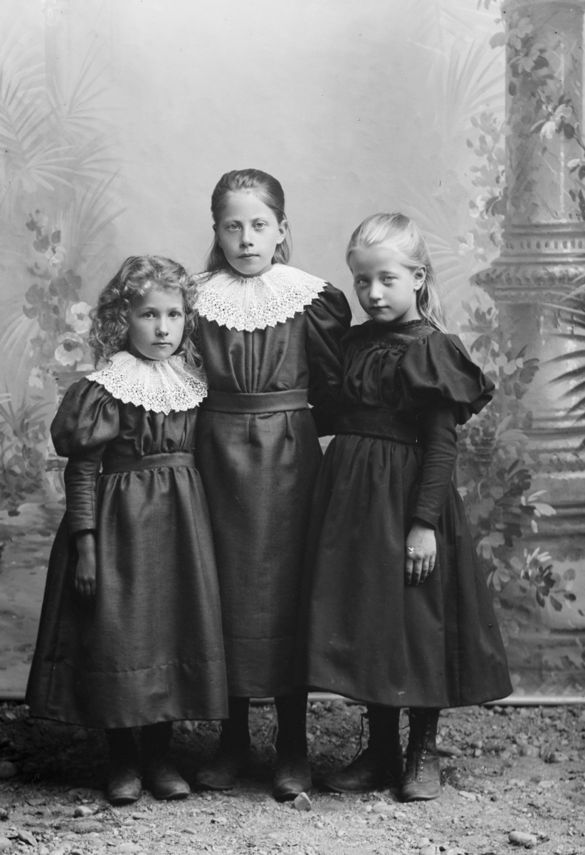 Gruppe, tre småjenter, ca. fire - åtte år, står ved kulisse, helfigur. Mari Bakkens (Bokken?) barn
