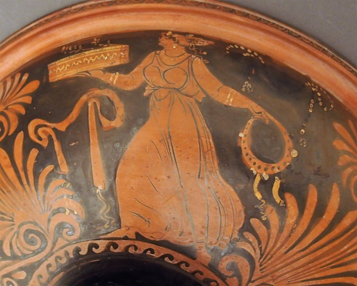 I skålens bunn naken mann (Dionysos) og kvinne med tamburin (mænade). Under dem en eggstav (kymation). Motivet er omgitt av løpende hund i sirkelform. På hankene hare og fugl. På undersiden palmettfrise (anthemion),løpende hund, mænade med tamburin og tromme og naken mann med olivengren (Apollon).