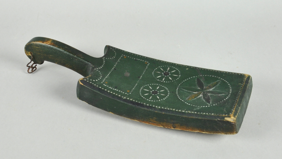 Banketre av ett trestykke, med rosetter på klubben. Banketreet er grønnmalt og lite brukt.