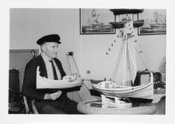 Håkon M. Aronsen viser frem modellbåter hjemme i stua.