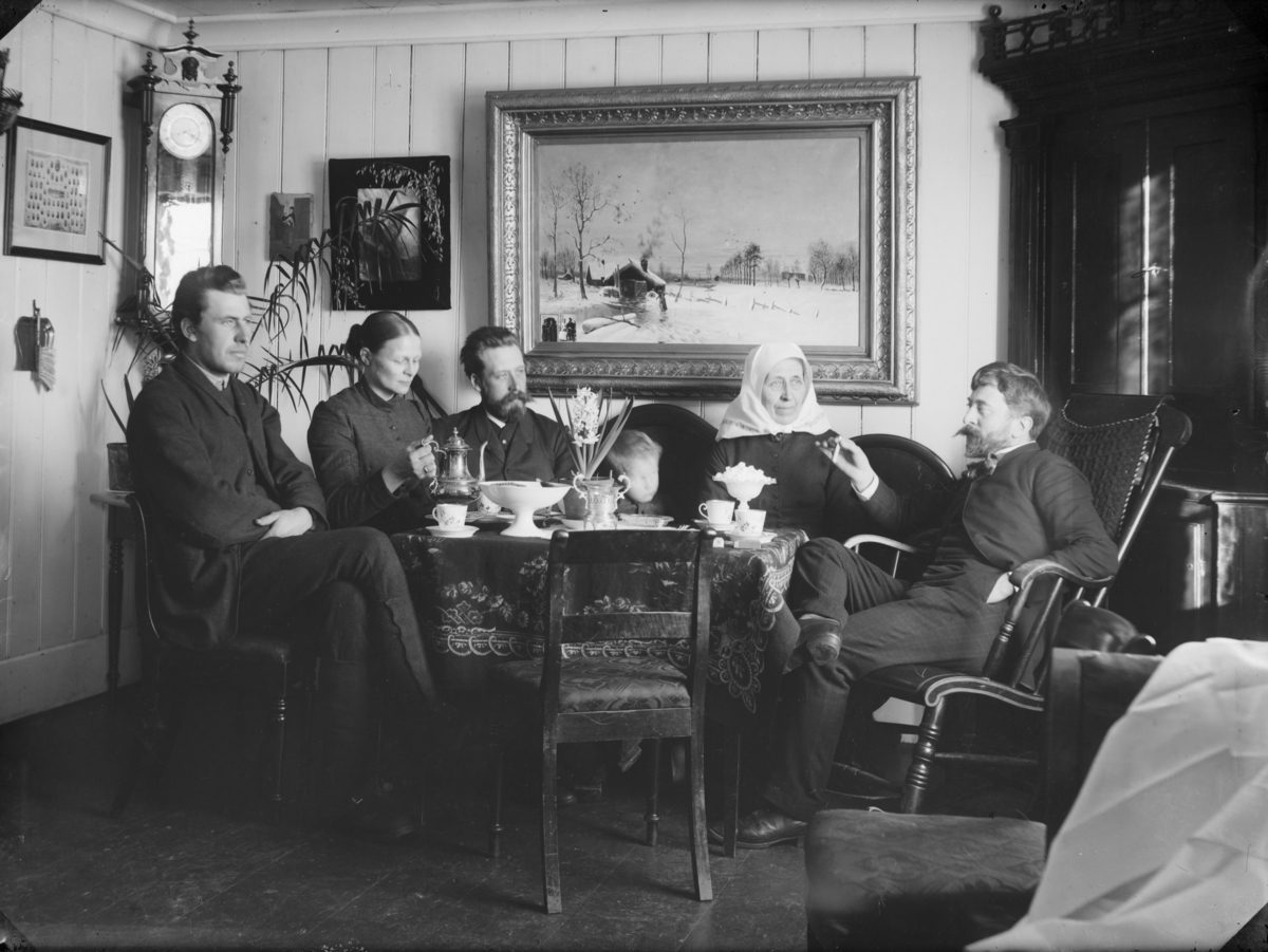 Fem voksne og et barn rundt kaffebordet i stuen på Skoug gård