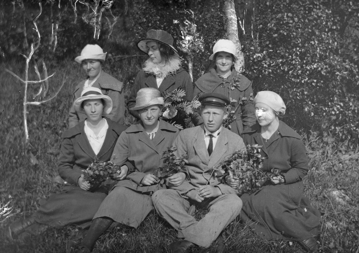 Seks kvinner og en mann sitter i gresset.