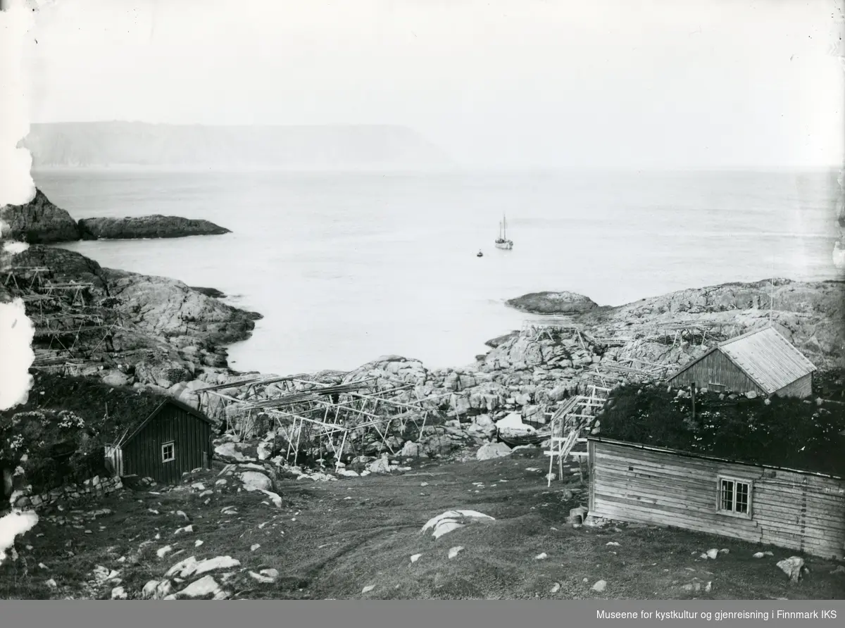 Helnes. Naust, fiskehjeller og rorbuer med torvtak. Fiskebåter i sjøen. Ca. 1895.