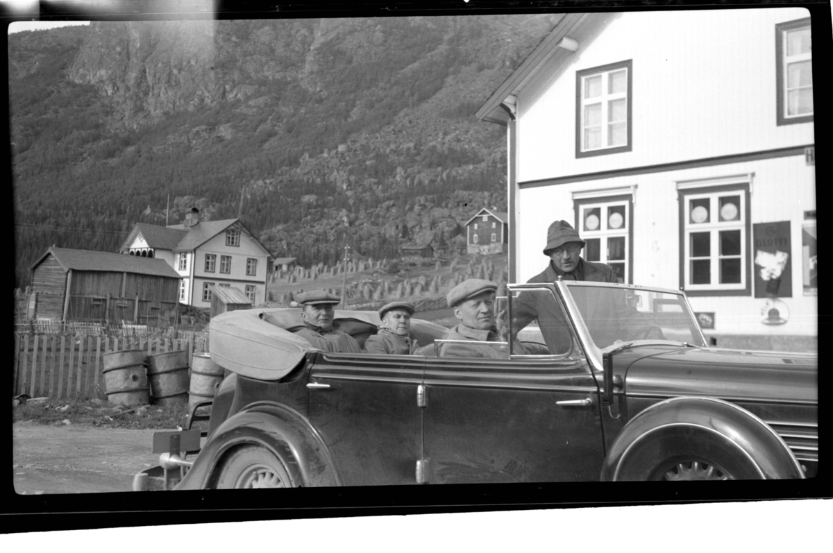 Johan Buratti, Erling Lorck sitter bak i bilen (Buick 1934-35 convertible sedan) mens Harsem sitter i forsetet sammen med stående Rolf Sundt sr., Vannevik, Hemsedal. To gårder ligger i bakgrunnen
. Fotografert 1938.