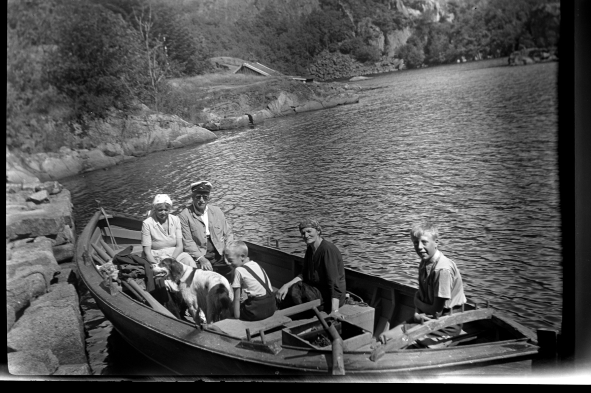 Ekteparat Agnes og Rolf sr. Sundt. og deres hund Uncas og husholderske Berta Venge sitter sammen med brødrene Odd og Petter Wilhelmsen i en robåt på tur til Spinnanger. Fotografert 2. august 1953.
