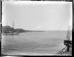 En seilskute ligger ankret opp innenfor Sandøy, og en robåt 