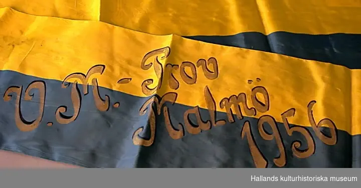 Blå-gult konstsidenband med målad guldtext: "V.M.-Prov Malmö 1956".