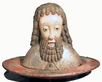 Träskulptur avbildande Johannes Döparens huvud på ett fat.
