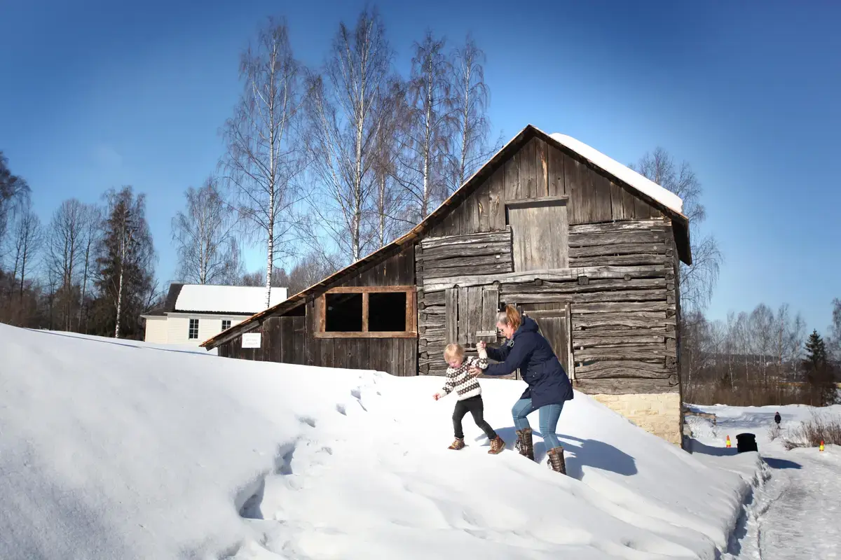 Besøkende i låven i snøen ute på friluftsmuseet