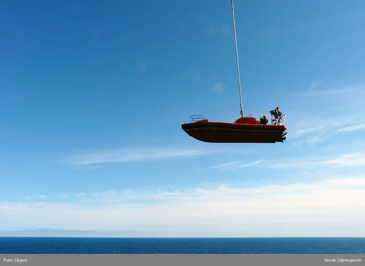 To personer har tatt plass i MOB-båten (mann over bord-båten) på Draugen, og skal heises på sjøen ved hjelp av en heisekrane.