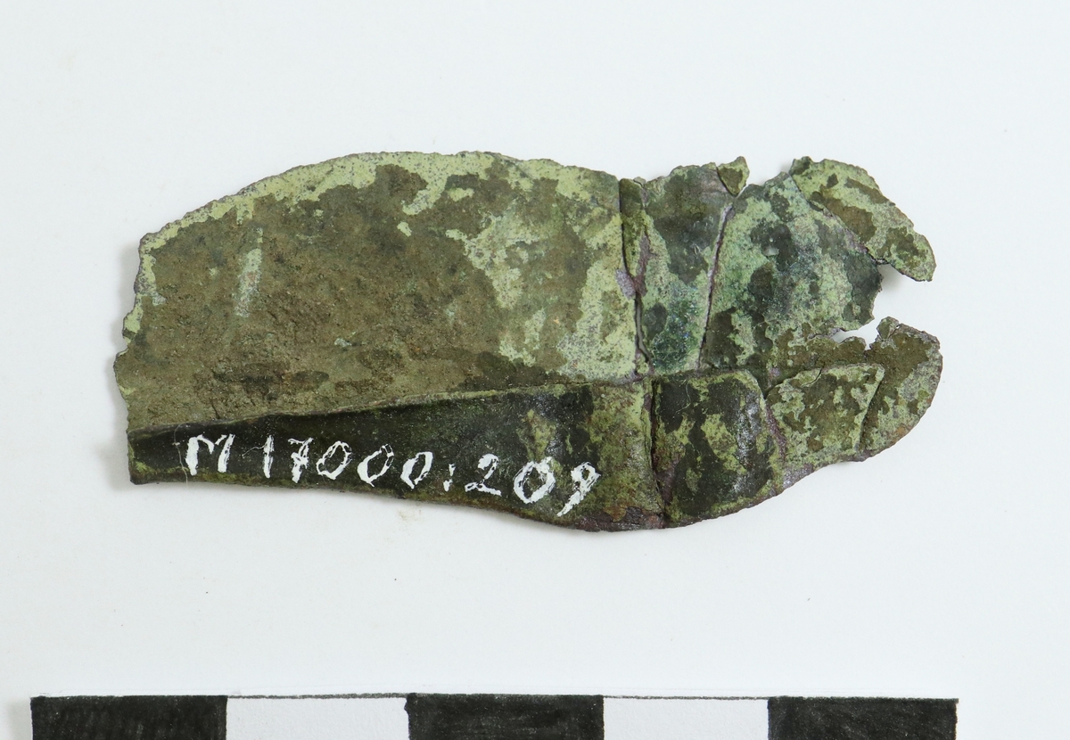 Fragment av bronsplåt med vikt kant. Spår av bearbetning med mejsel i parrallella rader.