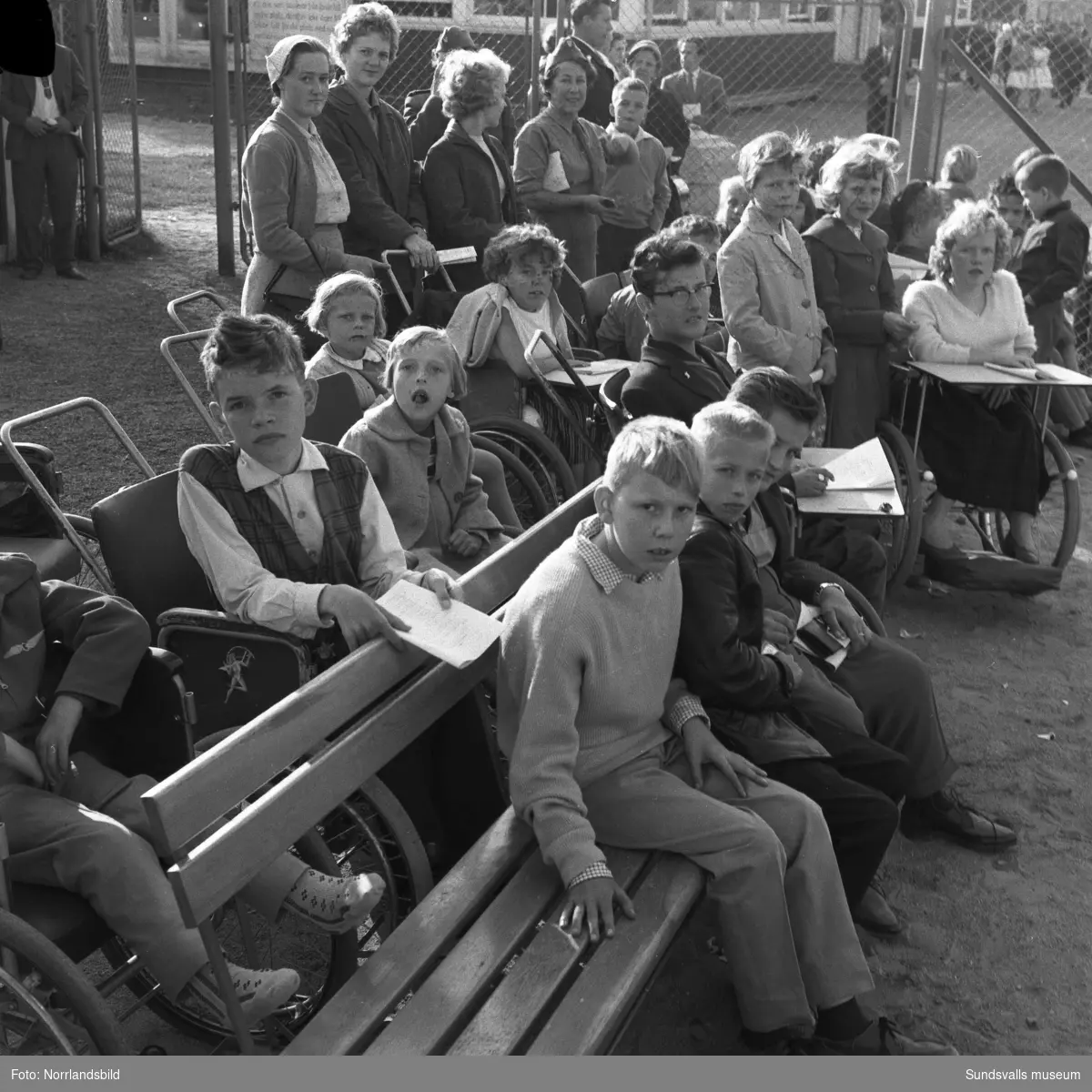 En grupp barn från Vanföreanstalten i Härnösand besöker Bergsåkers travbana, ett populärt utflyktsmål enligt reportaget i Dagbladet 1959. Tre av de som är med på bilden är: Gerd Söderberg, Sven Hellström och Emmy Tieusonen.