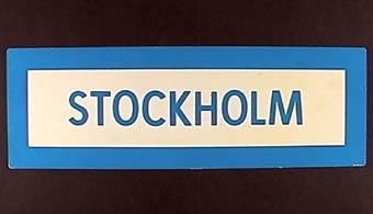 Långsmal dubbelsidig plastskylt med blå ram och text på vit botten: "GÖTEBORG"

Text på motsatt sida:
"STOCKHOLM"