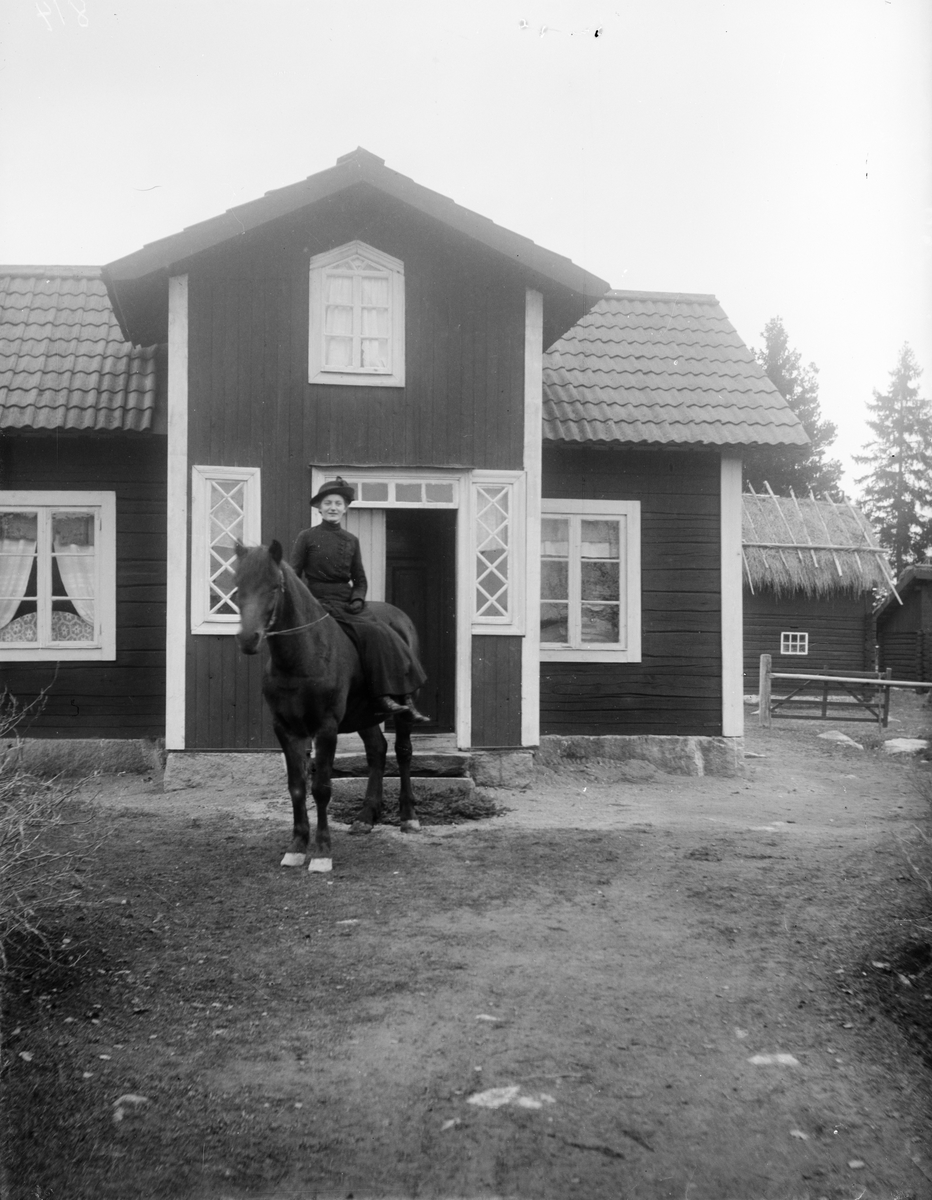 Kvinna till häst framför bostadshus