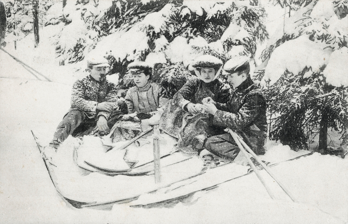 Postkort. Motivet på kortets fremside viser menn og kvinner under en rast på skitur.