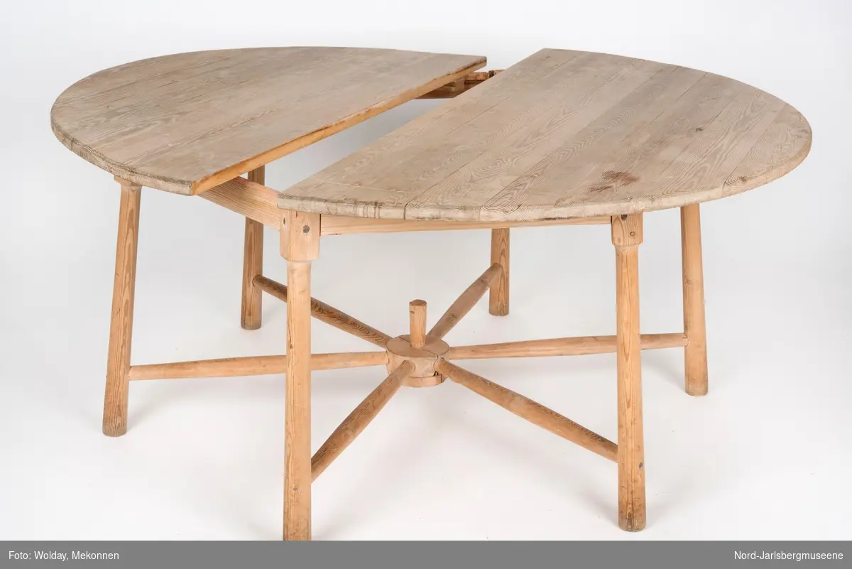 Rundt, umalt bord med seks tynne ben, som er festet med spiler mellom bena, inspirert av kjerrehjul. Bordplaten er delt i to (sekundært?)