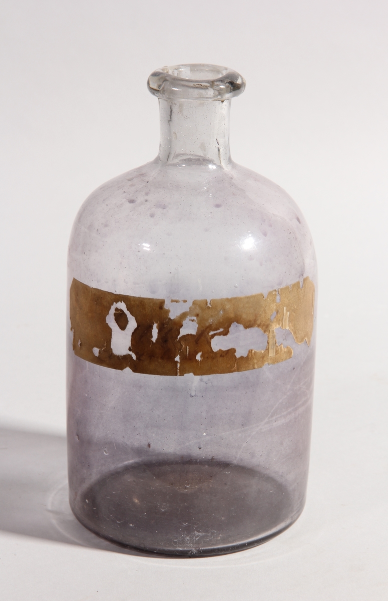 Flaska av ofärgat glas, cylindrisk med kort hals.