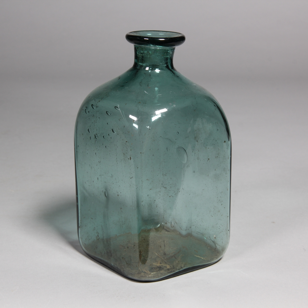 Flaska av grönt glas, kvadratisk med utvikt mynning.