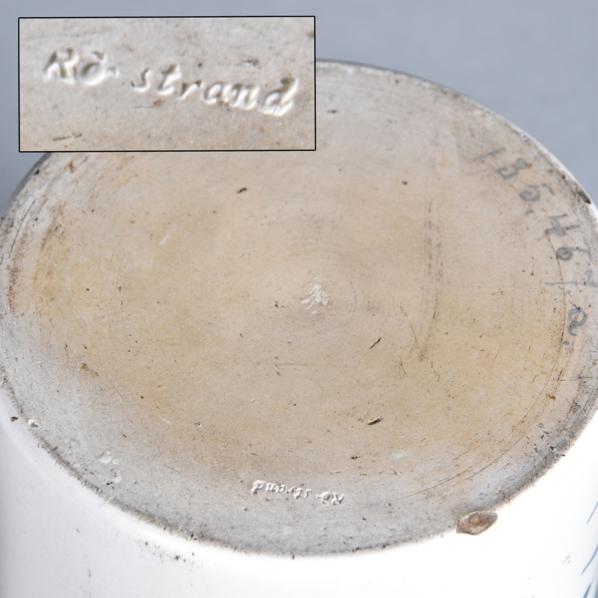 Apoteksburk av vitglaserat flintgods, cylindrisk. Lock av papp. Blå text inskriven i lagerbladskrans med krona.